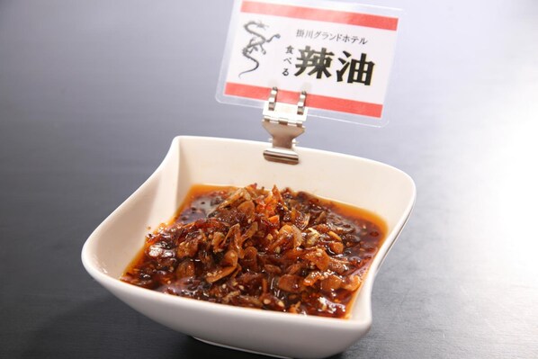 A bowl of spicy sauce with a sign above it.