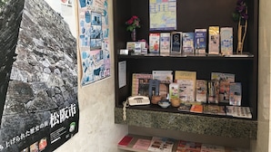 A display of informational posters and brochures, a stone wall, and a counter with various items. - Ace Inn Matsuzaka (Matsusaka)