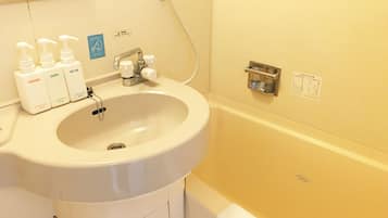 A bathroom with a sink, three bottles of toiletries, a faucet, and a bathtub.