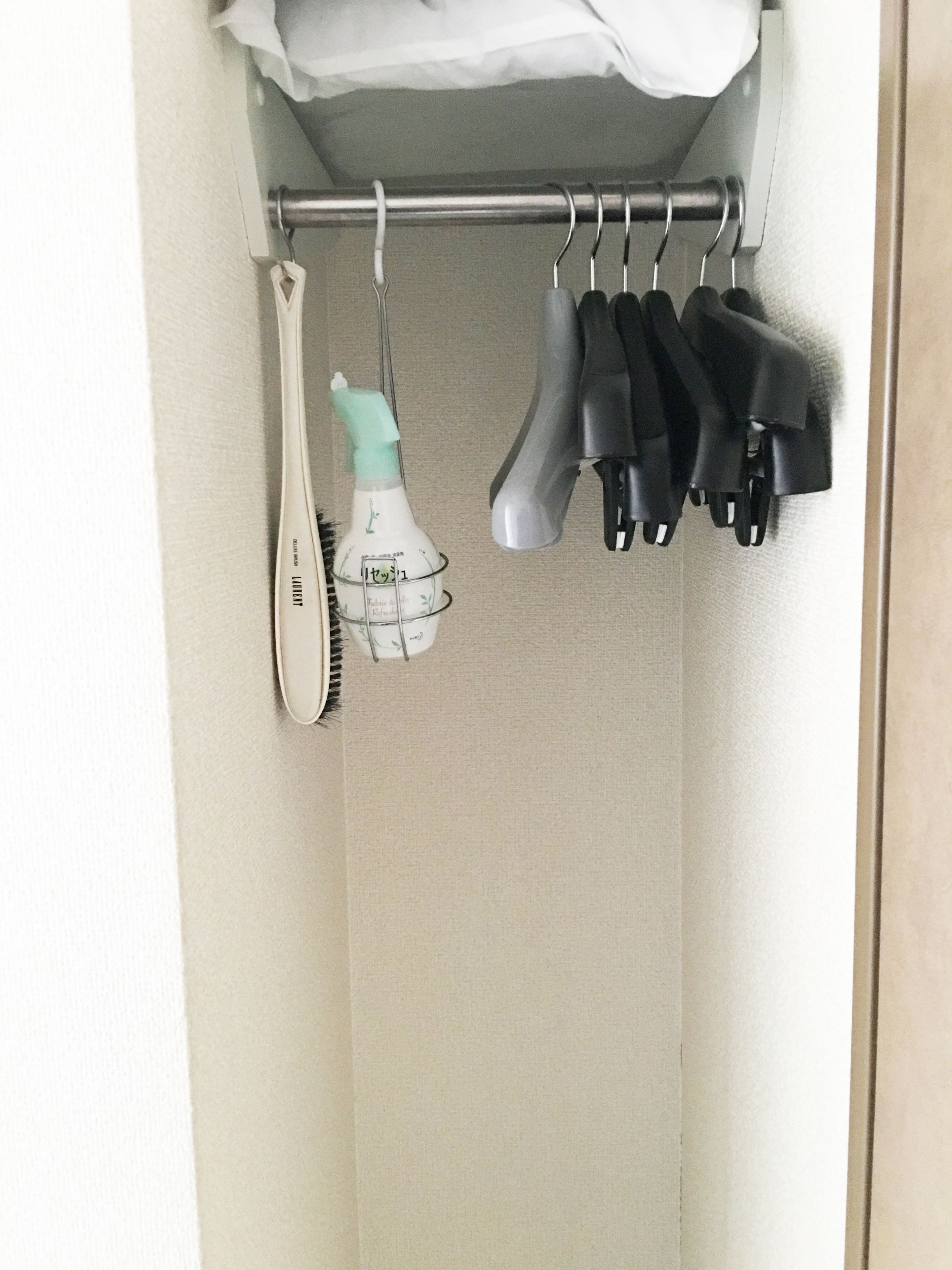 A closet with a hanging rack holding various hair care items, including a spray bottle, a brush, and multiple hair clips.