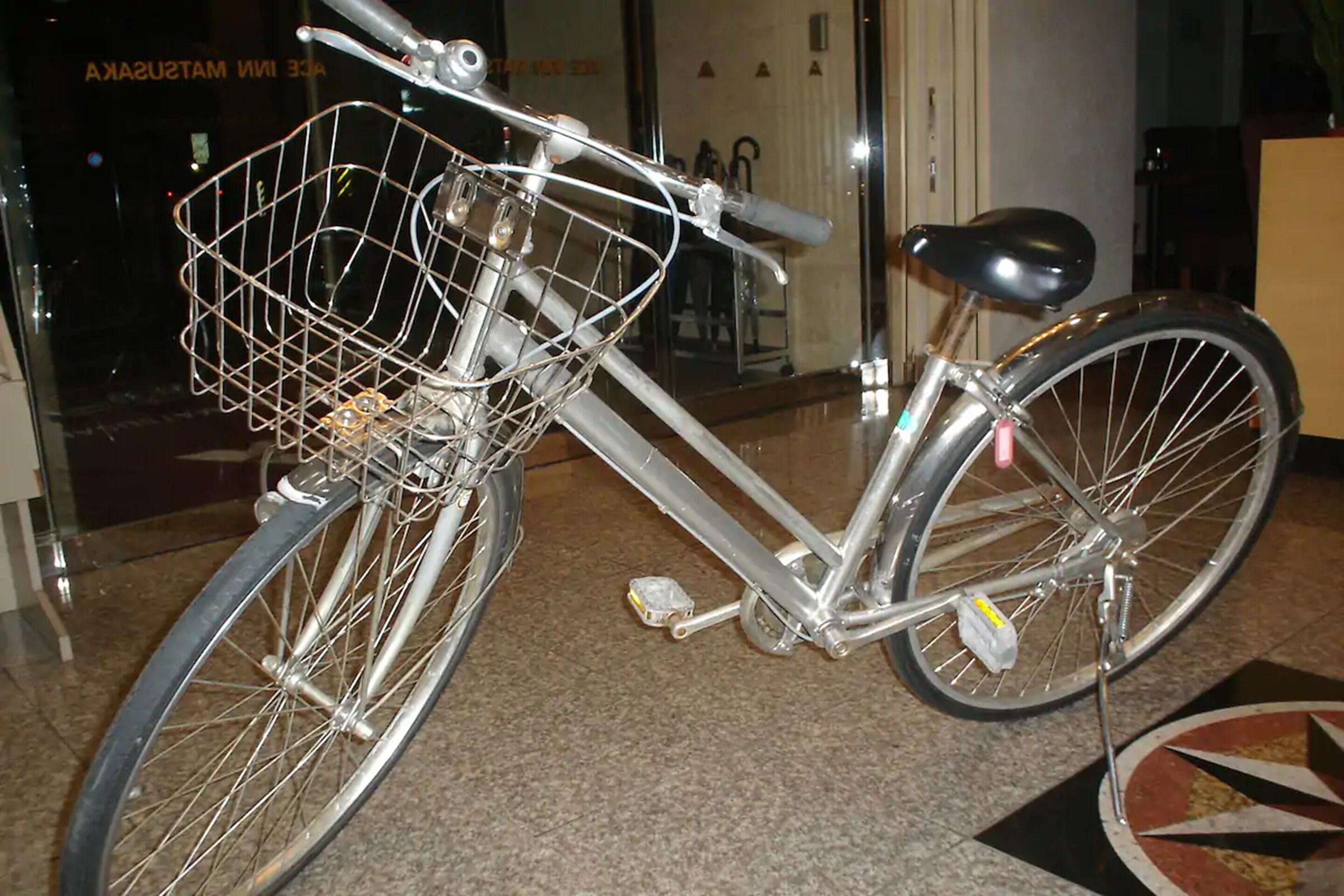 A bicycle with a basket, handlebars, and a seat, parked indoors.