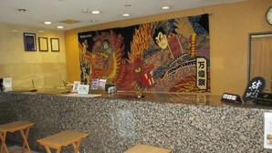 A reception area with a counter, two wooden stools, and a large decorative mural on the wall. - Ace Inn Kariya (Kariya)