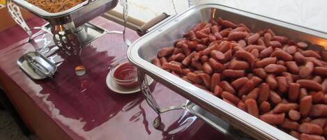 A buffet table with two metal serving trays, one containing a dish with noodles and the other filled with red kidney beans.