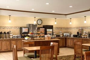 Una cocina de hotel con armarios de madera, un mostrador tipo buffet y un reloj en la pared.