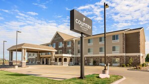 A Country Inn & Suites building with a covered entrance, multiple windows, and a clear sky. - Country Inn & Suites by Radisson, Minot, ND (Minot)
