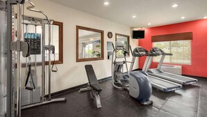 A gym with exercise equipment, a bench, treadmills, and a TV on the wall. - Country Inn & Suites by Radisson, Minot, ND (Minot)