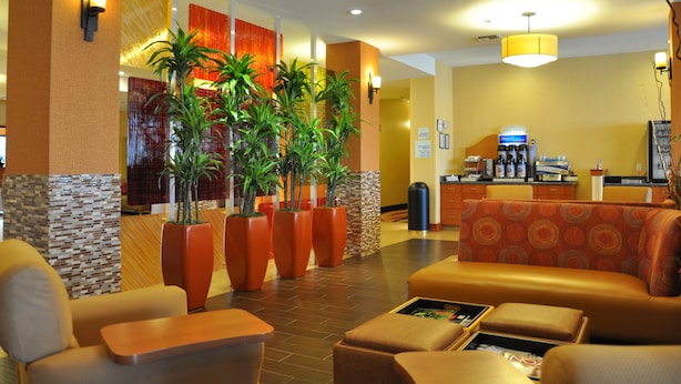 A hotel lobby with seating areas, potted plants, and a reception desk. - Holiday Inn Express Hotel & Suites Prattville South by IHG (Prattville)