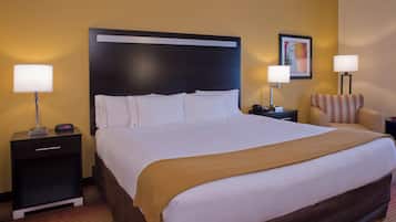 A hotel room with a large bed, two bedside tables, a chair, and a painting on the wall.