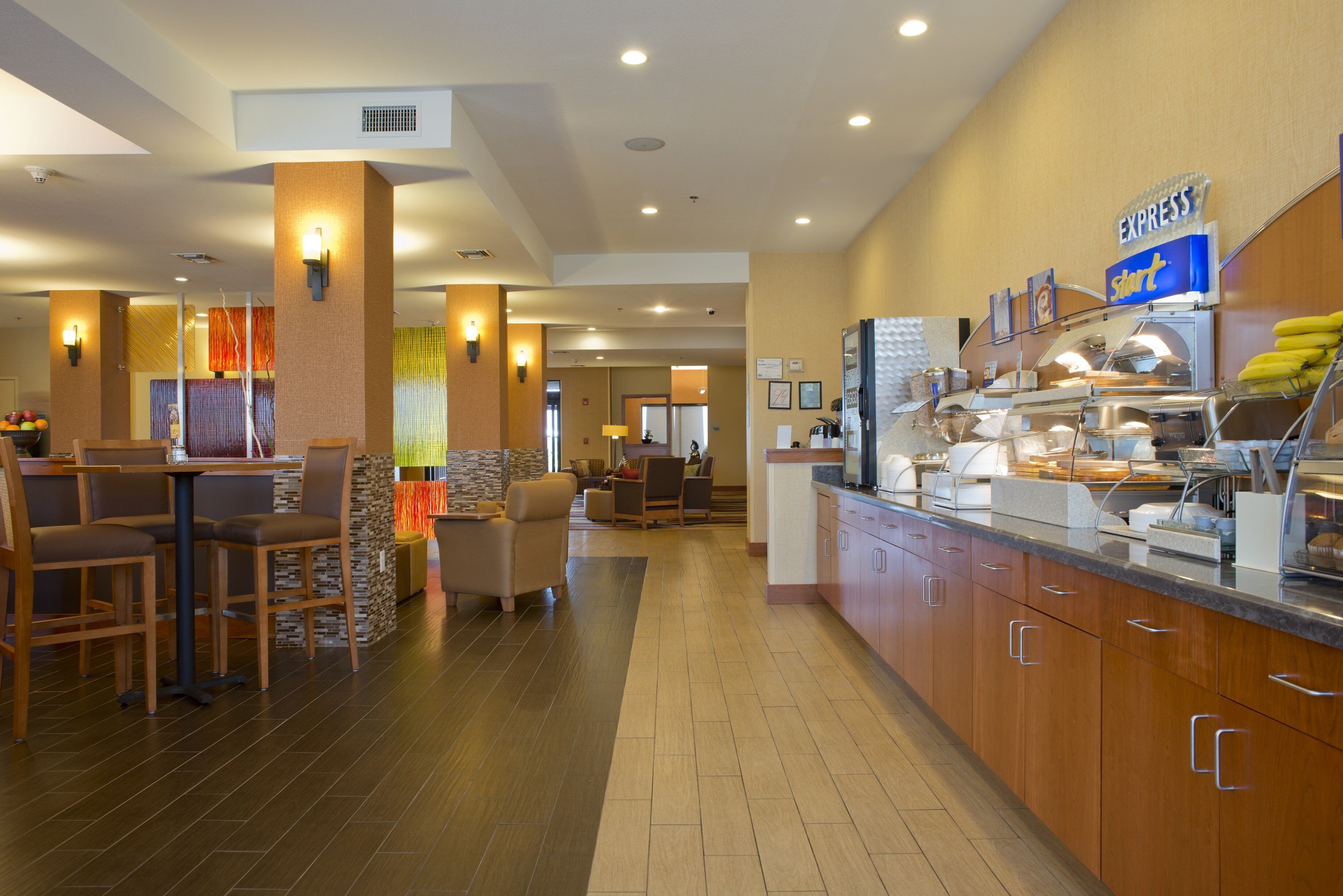 Um saguão de hotel com balcão de recepção, área de estar e mesa de buffet.