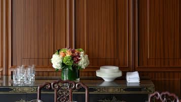 Un comedor formal con una mesa de madera dispuesta para una comida, una araña y un jarrón con flores.