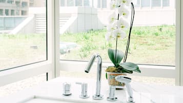 Une salle de bain moderne avec un lavabo blanc, des robinets chromés et une orchidée en pot.