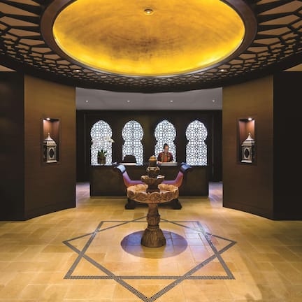 A lobby with a central fountain, patterned floor, and decorative lighting.