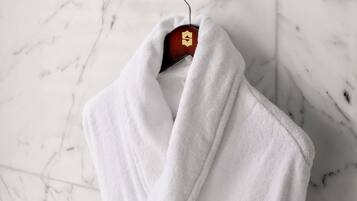 Een witte handdoek hangt aan een metalen handdoekhouder in een badkamer met een marmeren vloer.