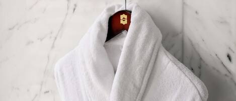 A white towel hanging on a metal towel rack in a bathroom with a marble floor.