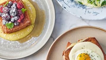 A breakfast setting with toast topped with berries and a poached egg, and a side salad.