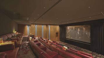 A theater with rows of red leather seats, a large screen, and a carpeted floor.