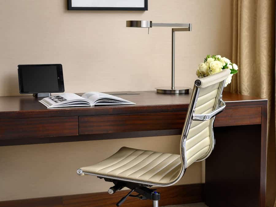 Una silla de oficina moderna con asiento y respaldo acolchados, estructura metálica y reposapiés.