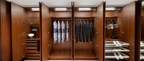 A walk-in closet with wooden doors, a marble floor, and multiple shelves and hanging spaces for clothes and shoes.