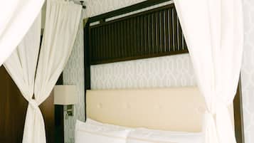 A bed with white linens, a headboard with a patterned design, and a nightstand with a lamp.