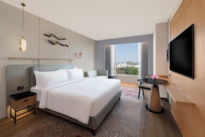 Une chambre d’hôtel moderne dotée d’un grand lit, d’une télévision, d’un bureau et d’une fenêtre donnant sur la ville.