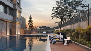 A modern building with a pool, outdoor seating, and a well-maintained garden. - The Aarlis Hotel Panchkula, Vignette Collection by IHG (Panchkula)