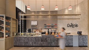 A bakery counter with a marble countertop, shelves with baked goods, and hanging pendant lights. - The Aarlis Hotel Panchkula, Vignette Collection by IHG (Panchkula)
