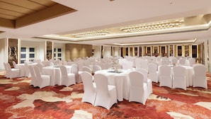 A banquet hall with round tables and white chairs, a patterned carpet, and a modern ceiling design. - The Aarlis Hotel Panchkula, Vignette Collection by IHG (Panchkula)