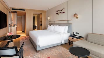 Una habitación de hotel moderna con una cama grande, un sofá, un escritorio con una silla y un televisor.
