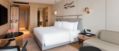 Una habitación de hotel moderna con una cama grande, un sofá, un escritorio con una silla y un televisor.