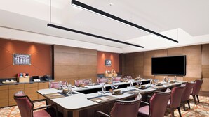 A conference room with a long table, multiple chairs, a flat-screen TV, and a wooden accent wall. - The Aarlis Hotel Panchkula, Vignette Collection by IHG (Panchkula)