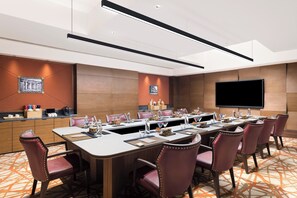 A conference room with a long table, multiple chairs, a flat-screen TV, and a wooden accent wall. - The Aarlis Hotel Panchkula, Vignette Collection by IHG (Panchkula)