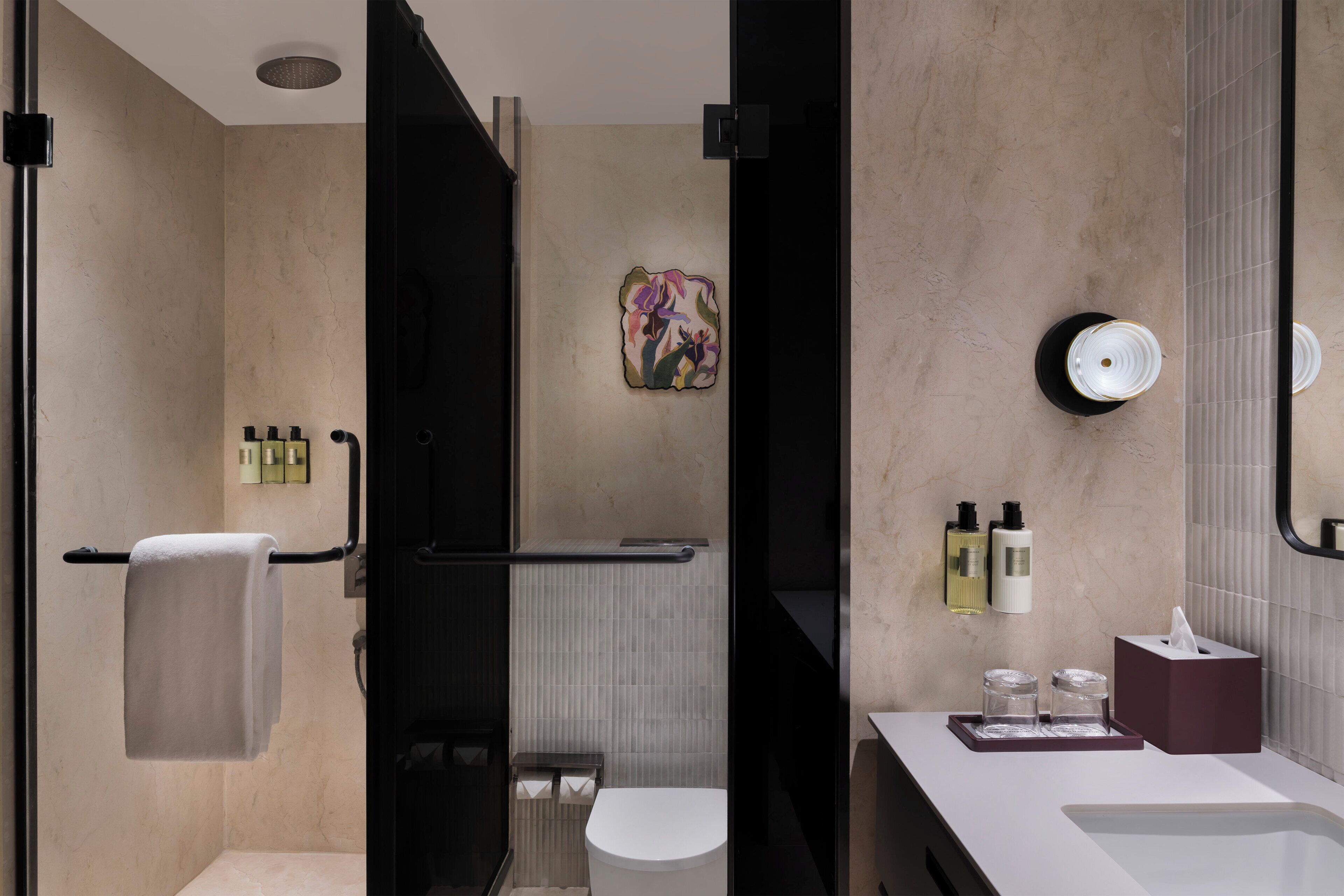 Un baño moderno con ducha, inodoro y lavamanos, que incluye un perchero, artículos de aseo y un espejo.