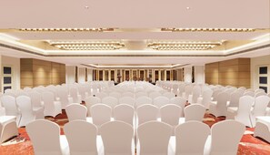 A large conference room with rows of white chairs, a stage with a podium, and a modern chandelier. - The Aarlis Hotel Panchkula, Vignette Collection by IHG (Panchkula)