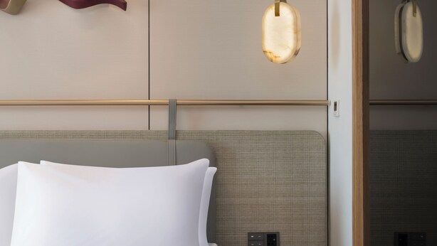 A hotel room with a bed, bedside tables, a wall-mounted light fixture, and a sliding door. - The Aarlis Hotel Panchkula, Vignette Collection by IHG (Panchkula)