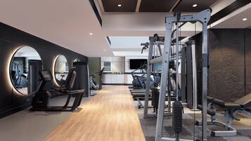 Un gimnasio moderno con equipamiento de ejercicio, piso de madera y un espejo grande.