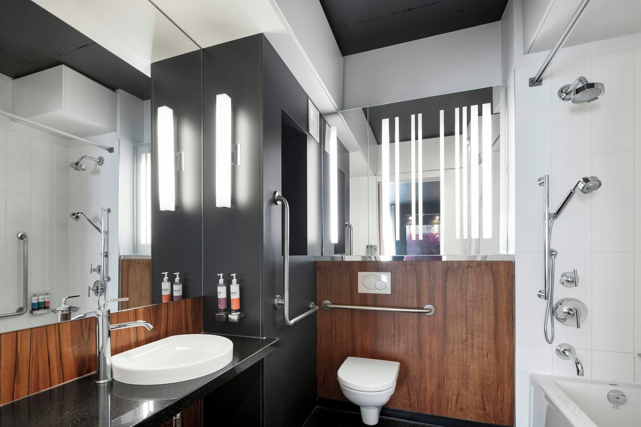 A modern bathroom with a white sink, a wooden vanity, a white toilet, and a shower area.