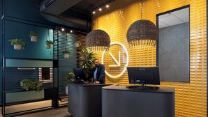 A modern reception area with two reception desks, a large mirror, and hanging wicker lamps.