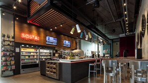 A modern bar area with a neon sign, shelves with snacks, and a bar counter.