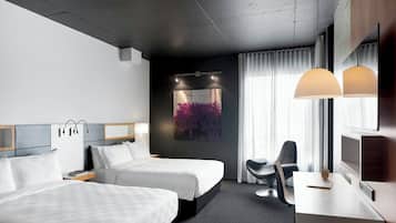 A hotel room with two beds, a desk, a chair, a TV, and a painting on the wall.