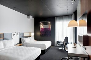 A hotel room with two beds, a desk, a chair, a TV, and a painting on the wall. - Alt Hotel Toronto Airport (Mississauga)