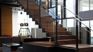 A modern staircase with glass railings and wooden steps, leading to an upper floor.