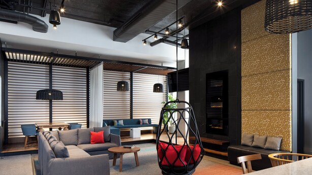A modern lounge area with a sectional sofa, a hanging chair, and a dining table.