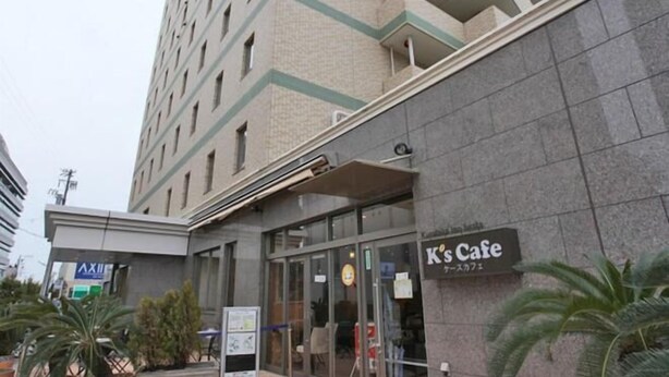 A building with a cafe entrance, a sign reading "K's Cafe," and a tall building in the background. - Kuretake Inn Iwata (Iwata)