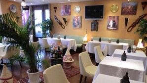A restaurant with multiple tables and chairs, a television mounted on the wall, and various wall decorations. - Kuretake Inn Iwata (Iwata)