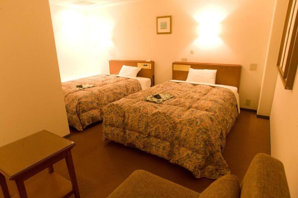 Ein Hotelzimmer mit zwei Betten, einem kleinen Tisch und einem Stuhl.