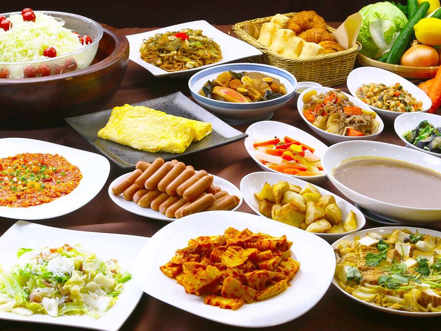 A variety of dishes on a table, including noodles, vegetables, and meat.