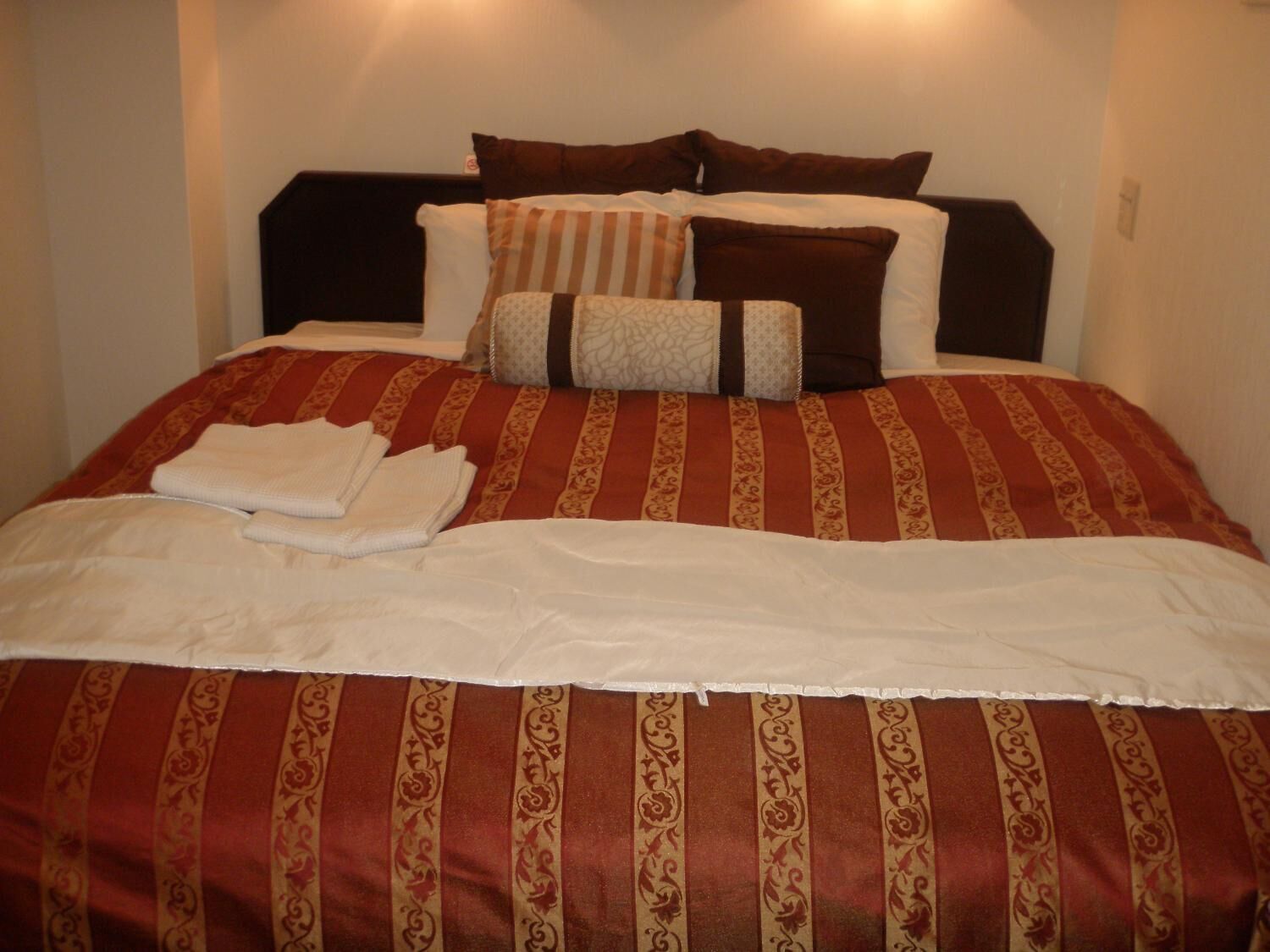 Un lit bien fait, avec une couvre-lit à rayures, des oreillers et des serviettes pliées.