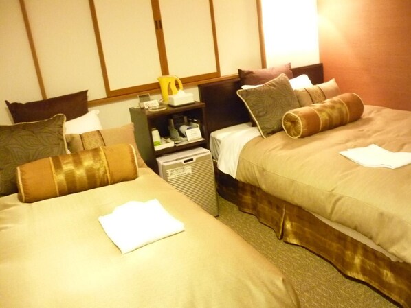 Une chambre d’hôtel avec deux lits, une table de chevet, un radiateur et une petite table sur laquelle se trouve une tasse jaune.