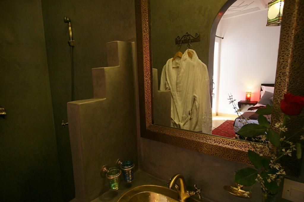 Een badkamer met een wastafel, spiegel en een badjas die aan een rek hangt.