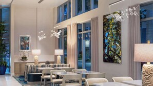 A modern hotel lobby with a seating area, large windows, and artwork on the walls.